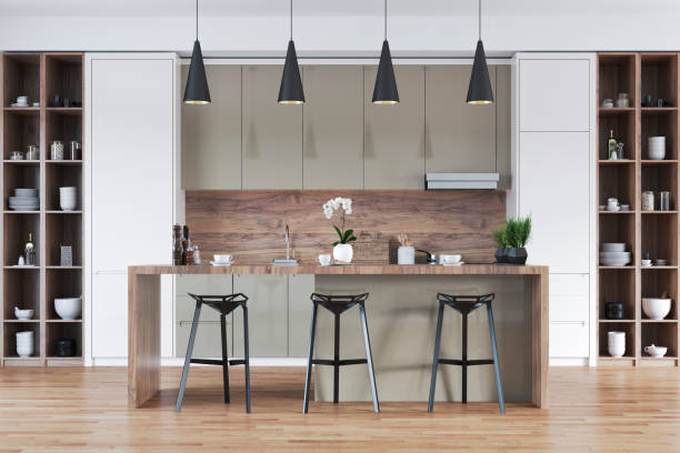 istock A front view of a modern white, hardwood and sand / oyster beige kitchen with rectangular breakfast kitchen island with stools, pendant lights 2154043771