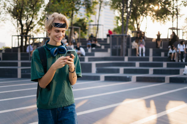 istock Smiling college student using mobile phone standing outside in campus 2154045531