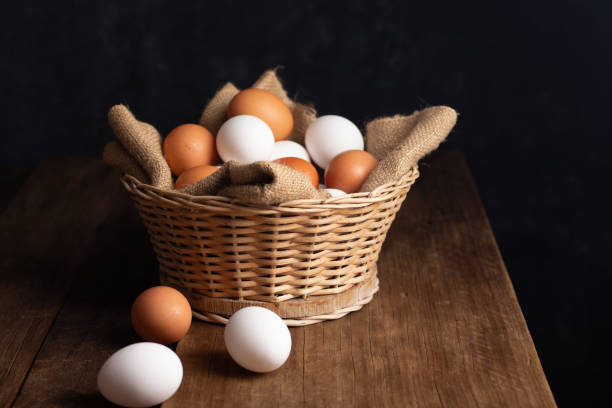 istock Basket of chicken eggs on a wooden table with dark background 2154046435