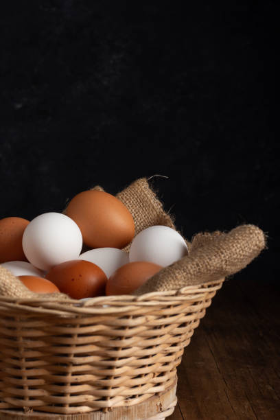 istock Basket of chicken eggs on a wooden table with dark background 2154046913