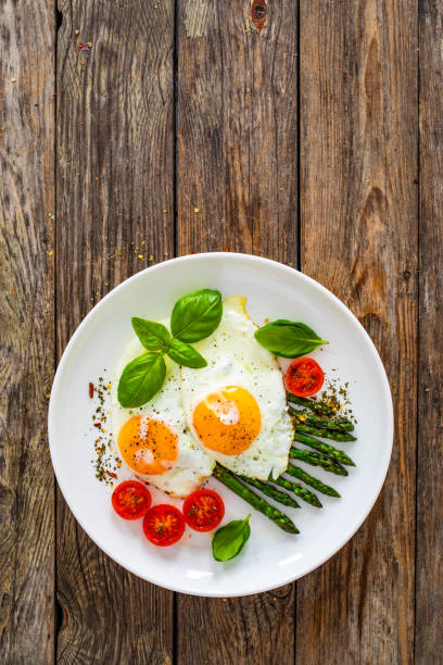 Sunny side up eggs with green asparagus on wooden table