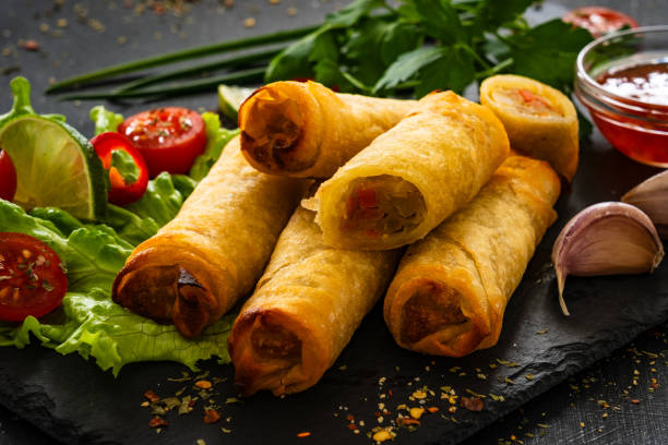 istock Spring rolls filled with meat and vegetables served with soy sauce on wooden table 2154050666