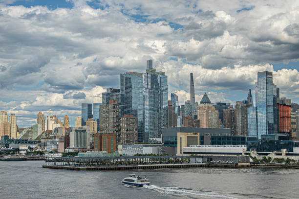 New York, NY, USA - August 1, 2023: Javits center, convention and exhibition facility, sits behind pier 76 under blue cloudscape. Urban jungle high rises around, some well and others not in the sun