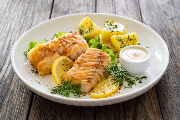istock Fried codfish fillet and boiled potatoes served on wooden table 2154051258