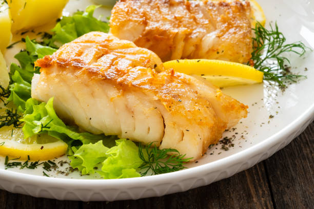 istock Fried codfish fillet and boiled potatoes served on wooden table 2154051832