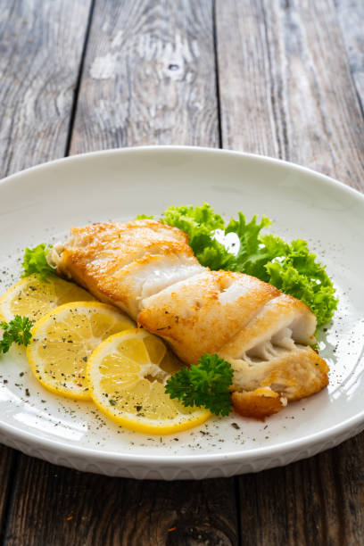 istock Fried halibut steak and fresh vegetables on wooden table 2154052510