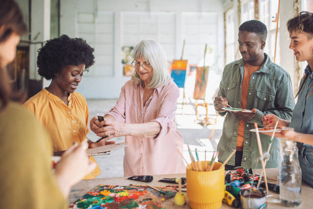 istock Senior art teacher guides diverse students in a bright studio, as they learn painting techniques on canvas with enthusiasm 2154053092