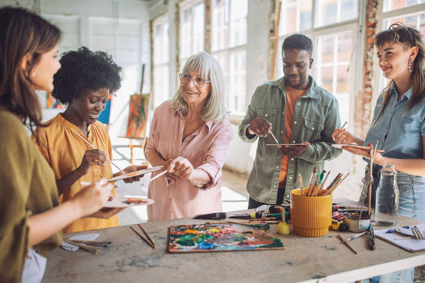 istock Art class in action: teacher guiding diverse students in painting workshop 2154053191