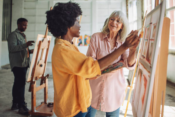 istock Art class in session: teacher guiding student with canvas painting 2154053828