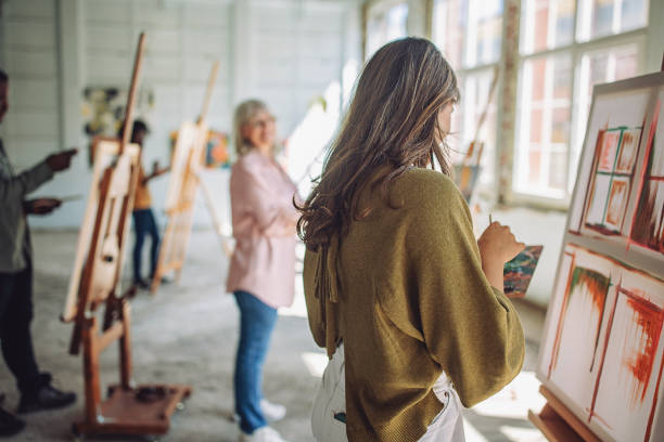 istock Art class engagement: teacher guiding students through canvas painting 2154053865