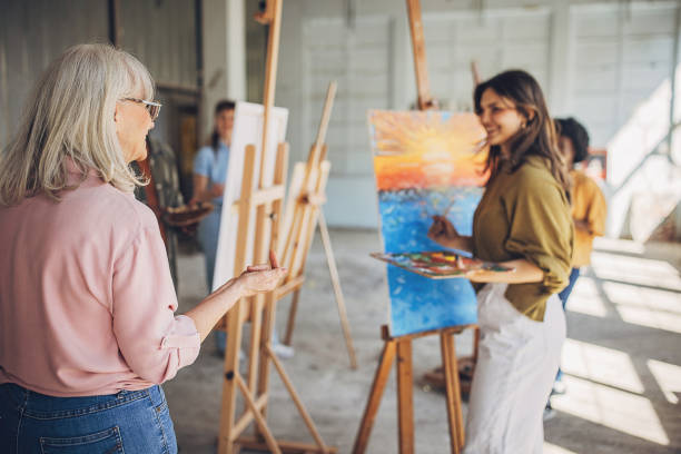 istock Art instructor guiding student in painting class 2154055335