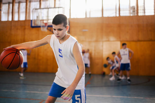 istock A junior basketball player dribbling a ball on training at court. 2154057775