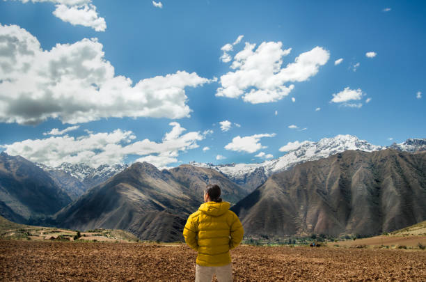 Latin hiker observing the mountains and the Andes mountain range on his way to the archeological site of Ollantaytambo in Cusco, Peru.