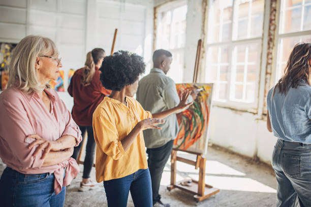 istock Art instruction in progress: teacher guiding students in painting class 2154065893