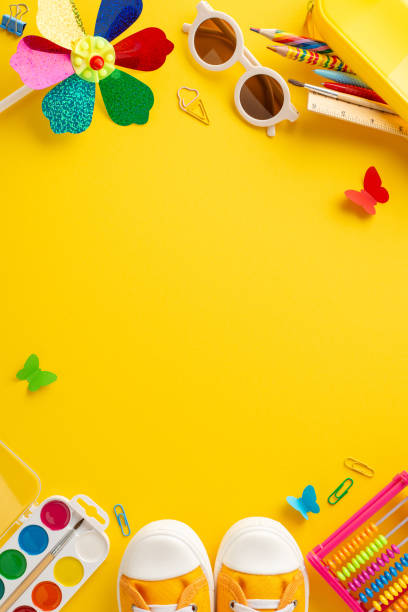 istock Creative summer program idea. Vertical top view of creativity supplies: colored pencils, paints, clips, outdoor gear - eyewear, sneakers, pinwheel, butterflies on yellow background with copy space 2154067604