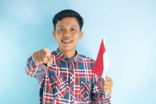 Happy child celebrating Independence Day, holding American flag in backyard,  looking at camera