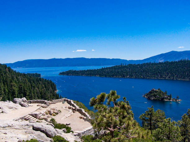 A hiker standing on boulders, enjoying the views of Fannette Island and Emerald Bay in the evening at Emerald Bay State Park, Lake Tahoe, California, USA.
