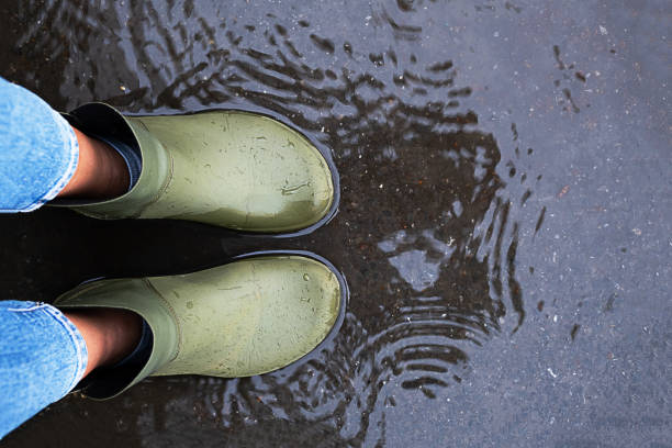 istock Woman wearing rubber boots standing in a puddle. 2154077795
