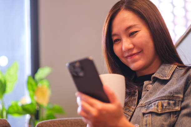 istock Portrait image of a young woman holding and using mobile phone while drinking coffee in cafe 2154078087