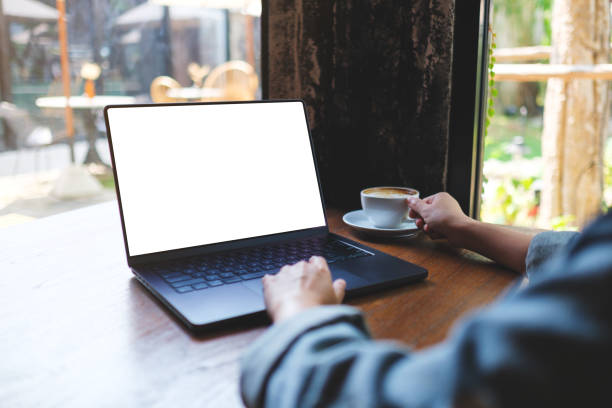 istock Mockup image of a woman working on laptop computer with blank white desktop screen while drinking coffee in cafe 2154078091