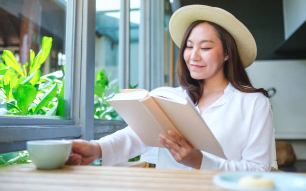 istock Portrait image of a beautiful young woman with hat drinking coffee while reading book 2154078106