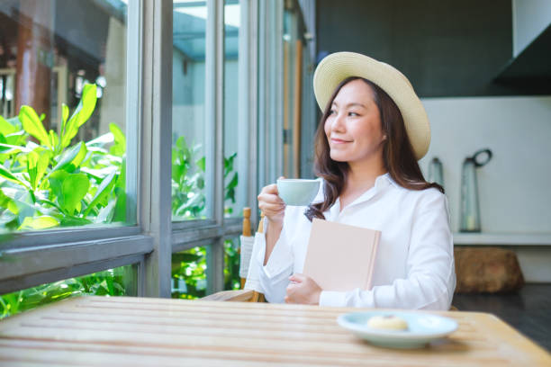 istock Portrait image of a beautiful young woman with hat drinking coffee while holding a book 2154078107