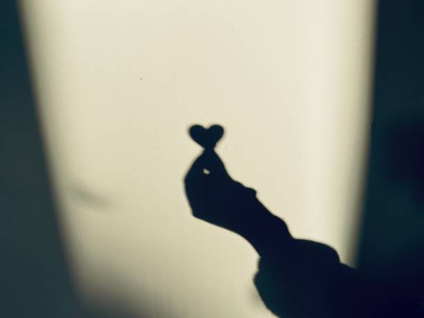 Hand holding heart reflection shadow on wall