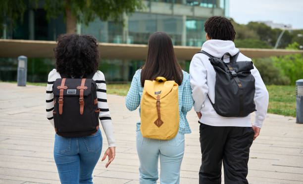 istock Three young students walking down a sidewalk to the University, each carrying a backpack 2154079871