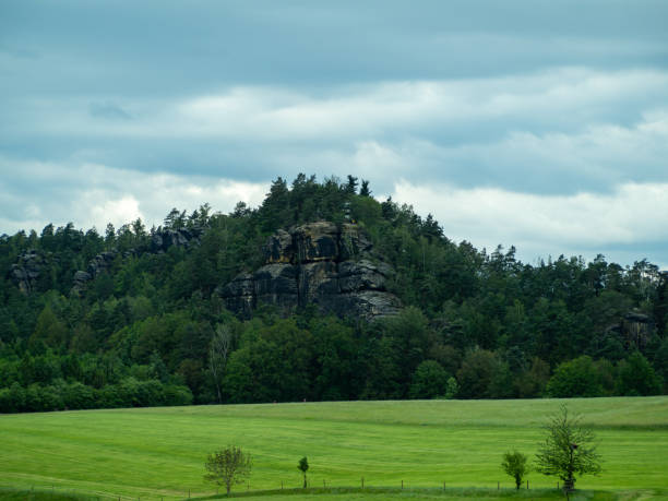 A mountain range with a cloudy sky in the background. The sky is dark and the mountains are covered in trees
