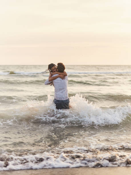 Young cheerful couple playing during summer day at sea. Copy space.