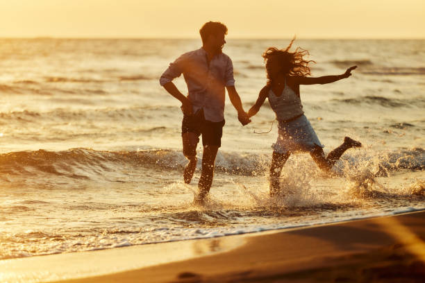 istock Cheerful couple running through sea on the beach at sunset. 2154086934