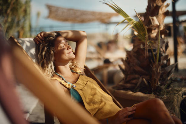 Smiling woman relaxing on a deck chair at the beach.
