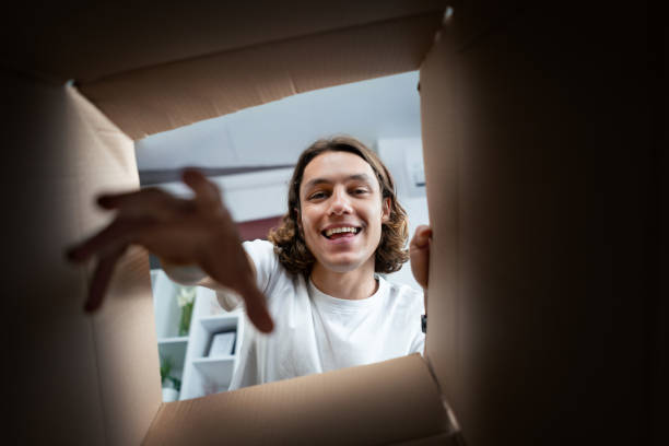 istock Happy Young Man Reaching Into A Cardboard Box At Home 2154087696