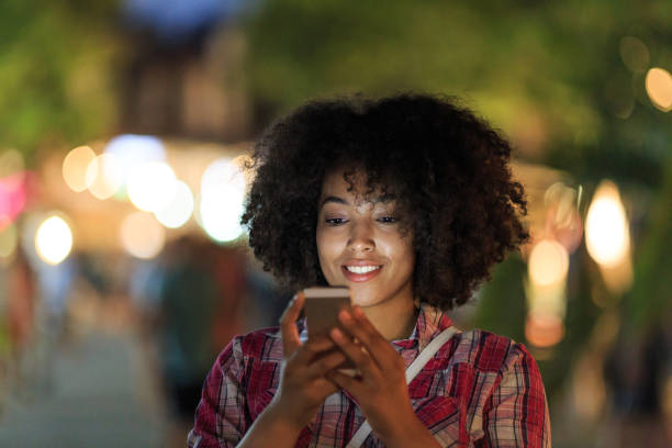 istock Woman browsing phone with city lights 2154092815