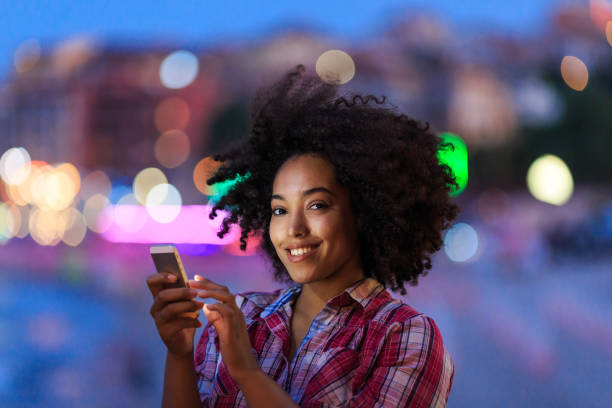 istock Smiling young lady with smartphone in evening 2154092817