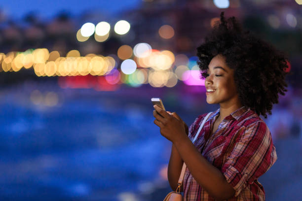 istock Smiling woman using phone with city lights behind 2154092828