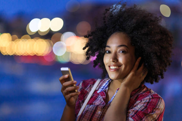 istock Happy woman with phone on urban night backdrop 2154092832