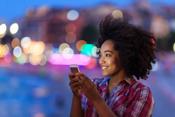 istock Woman with afro using smartphone at night 2154092840