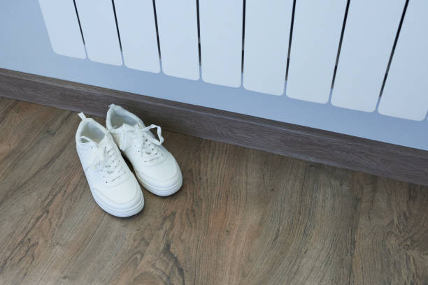 istock Heating radiator with shoes in the room. 2154096410