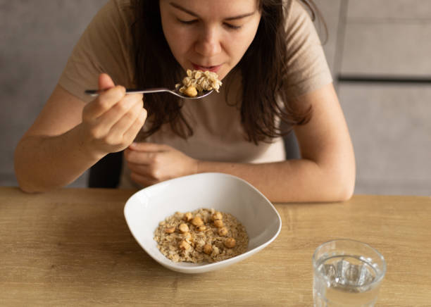 istock young woman eats oatmeal with nuts, a spoon with oatmeal 2154102088