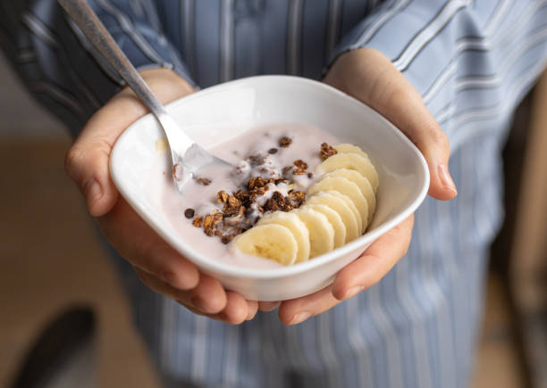 istock female hands, plate with granola, yogurt and bananas, top view 2154102155