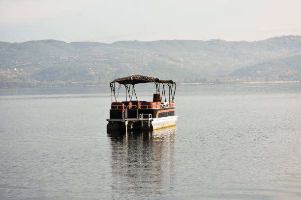 A narrowboat painted blue with white highlights tied to the riverside, alongside a smaller blue rowboat, reflecting the peaceful charm of waterside living during summer.