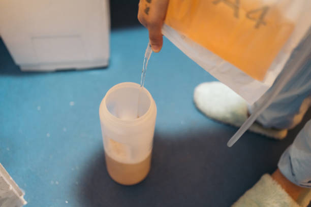 istock Hands holding a urinary catheter bag, filling a plastic sample container on the floor through a circular spout. 2154104420