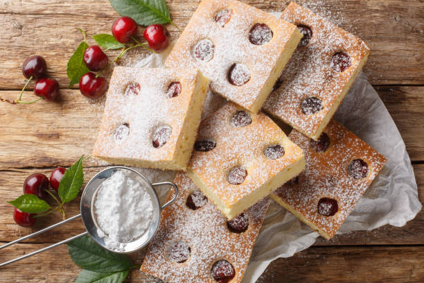 Fruity cherry cake known as Bublanina sprinkled with powdered sugar closeup on the parchment. Horizontal top view