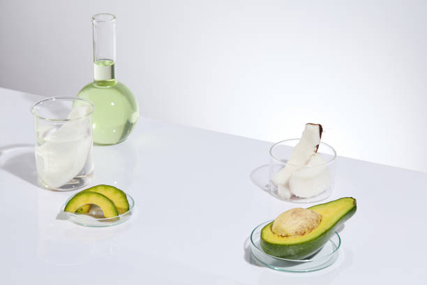 istock Top view photo on white texture, a boiling flask of light green liquid, a beaker with transparent fluid and a coconut piece and petri dishes of avocado. Empty space for adding text 2154108844