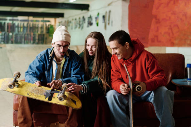 istock Two Guys And Girl Discussing Skateboards 2154110388