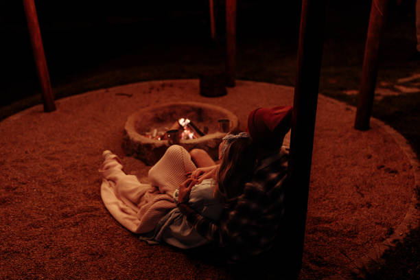 istock Couple leaning on a wooden pole, lying by a fire pit 2154111208