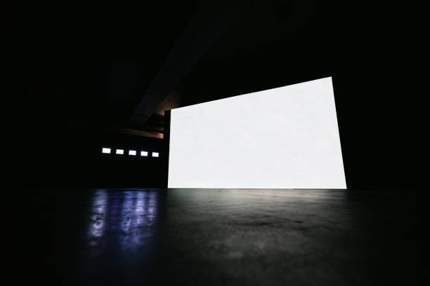 White big glowing digital screen and five small screens beside in dark hall interior with concrete floor and black wall.