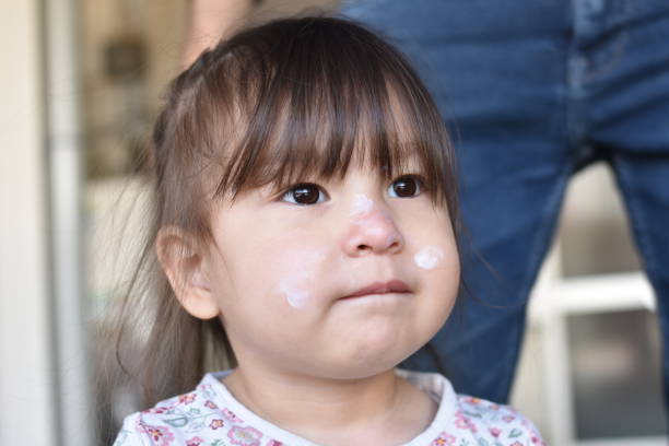 Baby girl applying sunscreen to play in the park