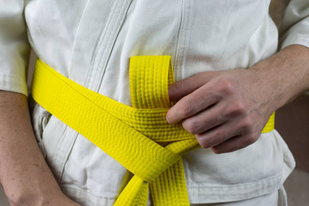 istock Male hands tighten yellow karate belt on kimono 2154113617